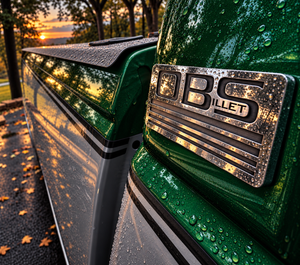 Metallic green OBS truck with polished pillar emblem and rain droplets at sunset